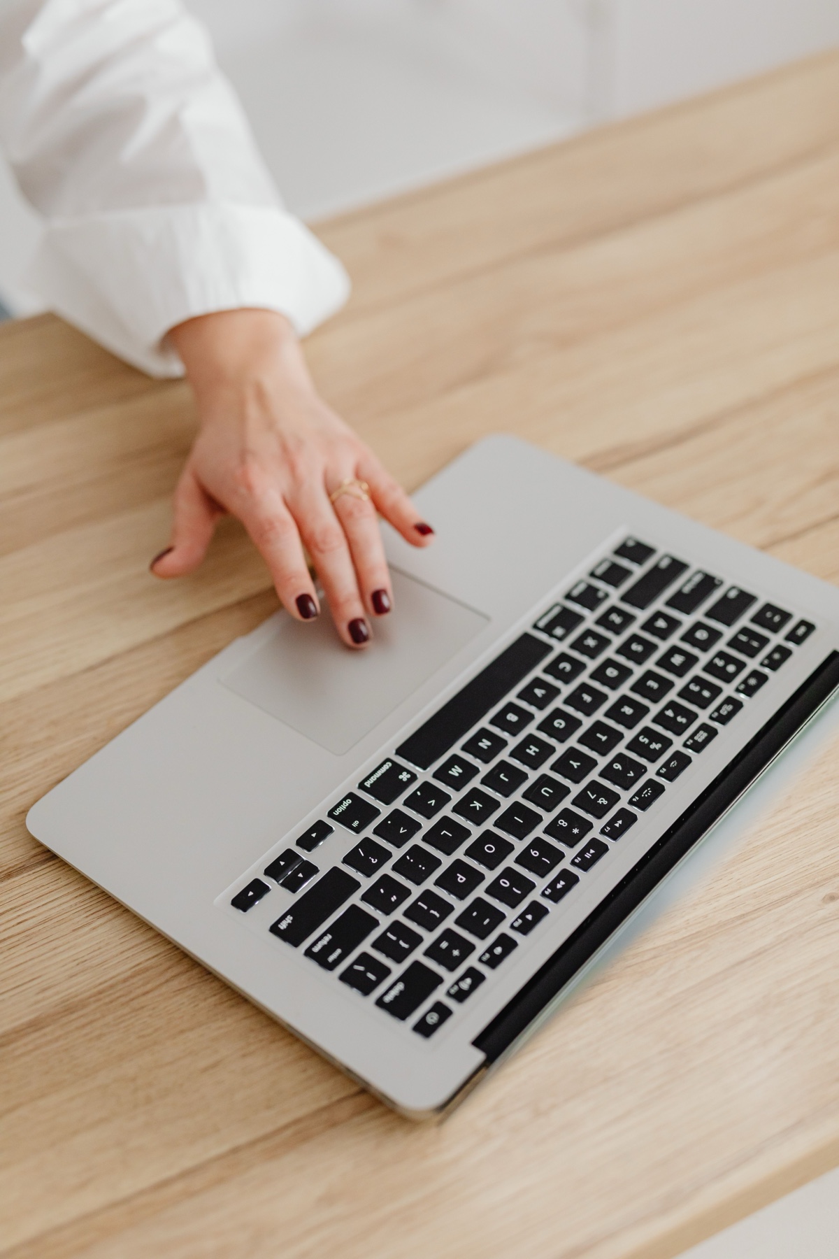 Main sur le clavier d'un ordinateur portable, bureau en bois clair